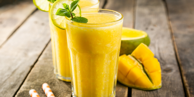木製の机の上に置かれたマンゴーとマンゴースムージー